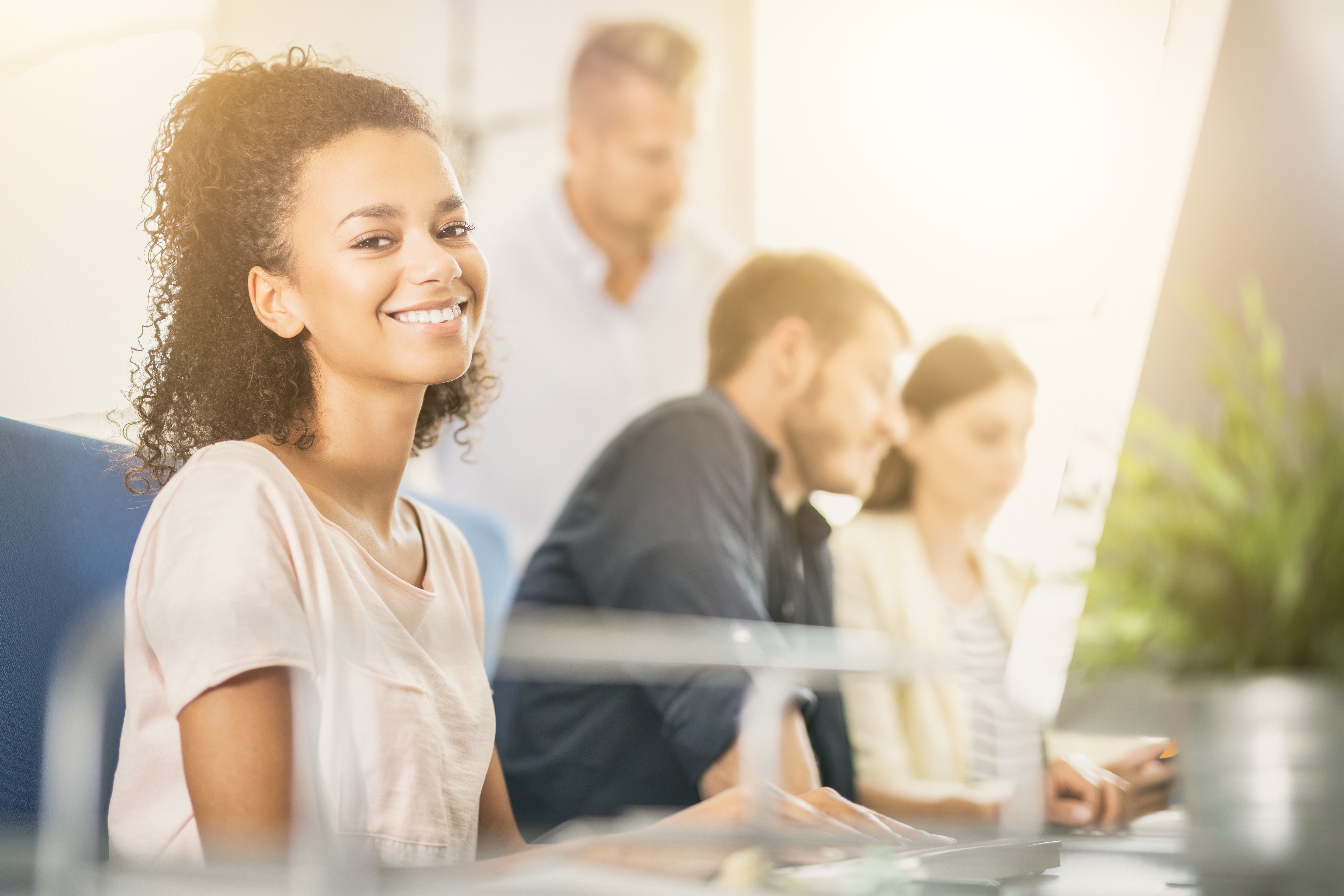 teacher smiling and sitting at desk with colleagues